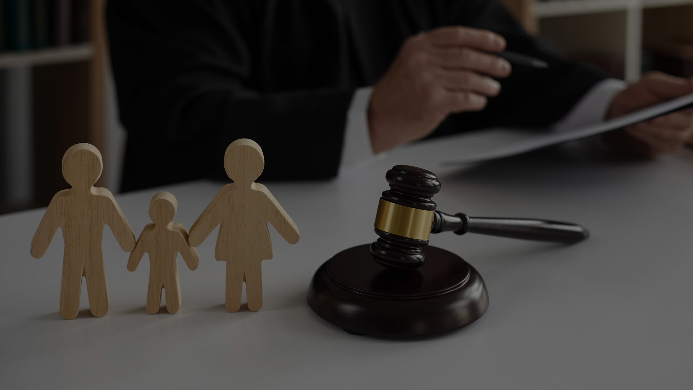 Three wooden figures representing family next to a gavel and attorney.